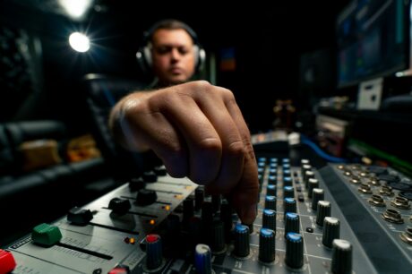 Concentrated sound engineer working at the mixing console in a music studio to record a soundtrack