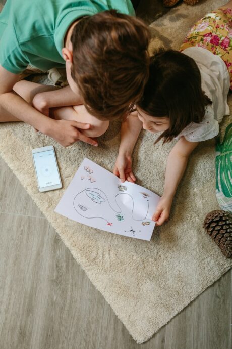 Top view of kids playing treasure hunt at home on the carpet